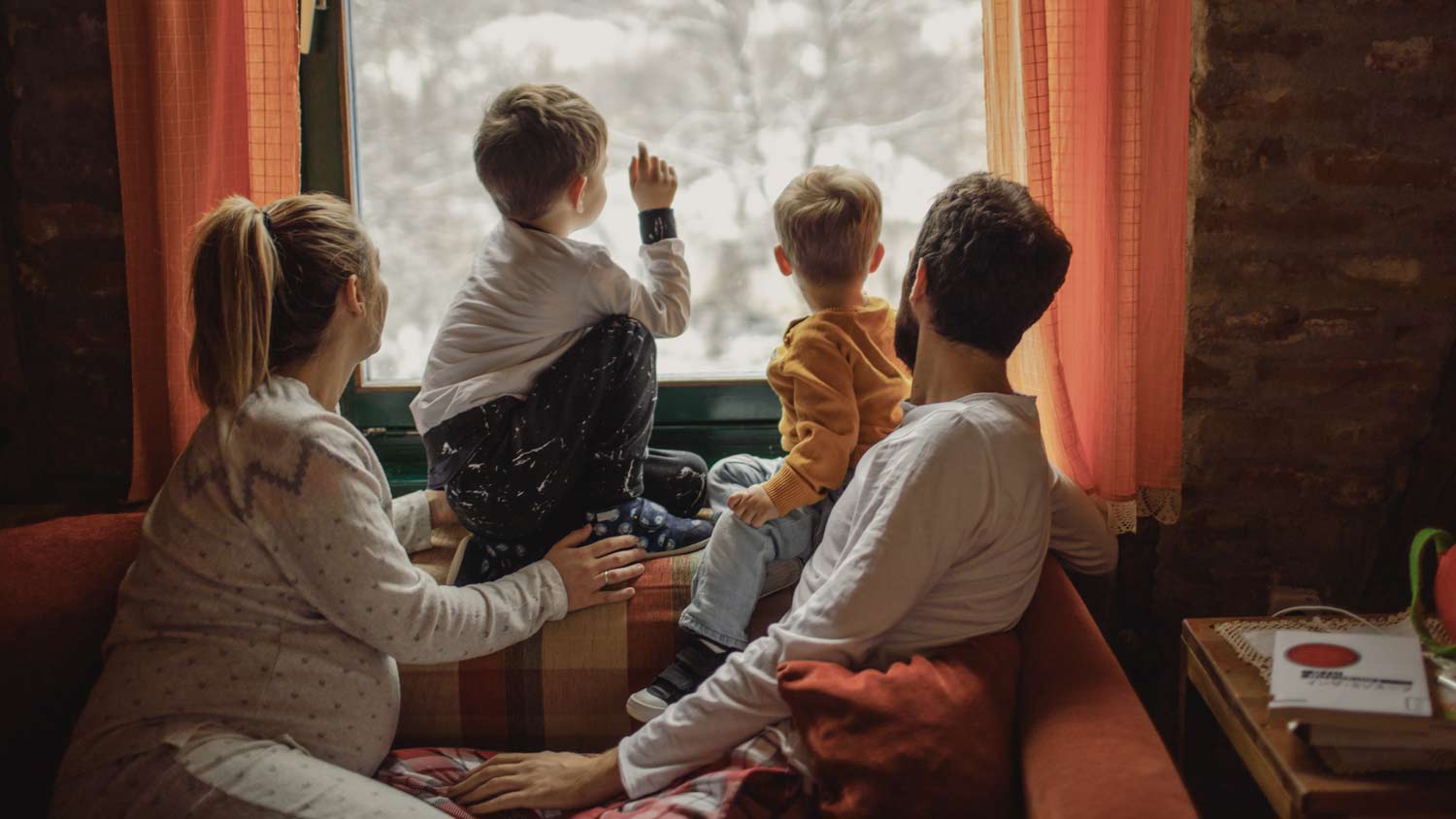 Family sitting cozy at home looking out the window