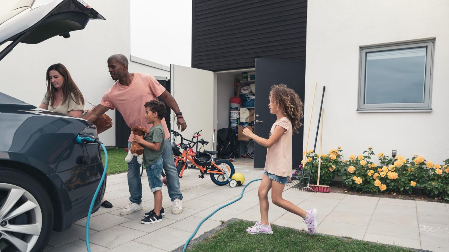 A family loading luggage in their car while charging it