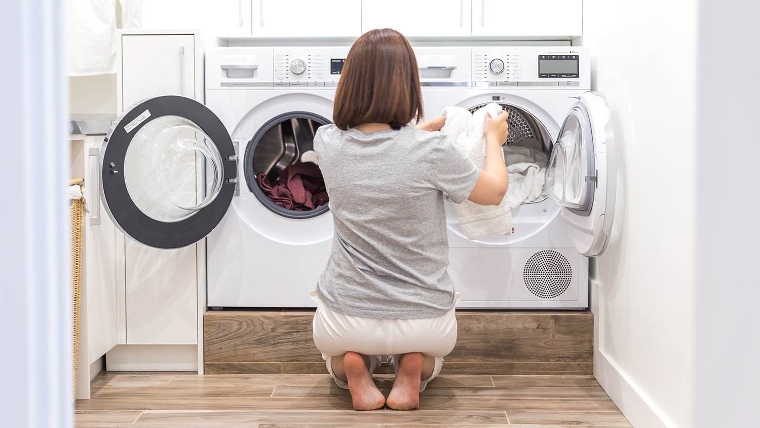 Woman crouching is loading washing machine