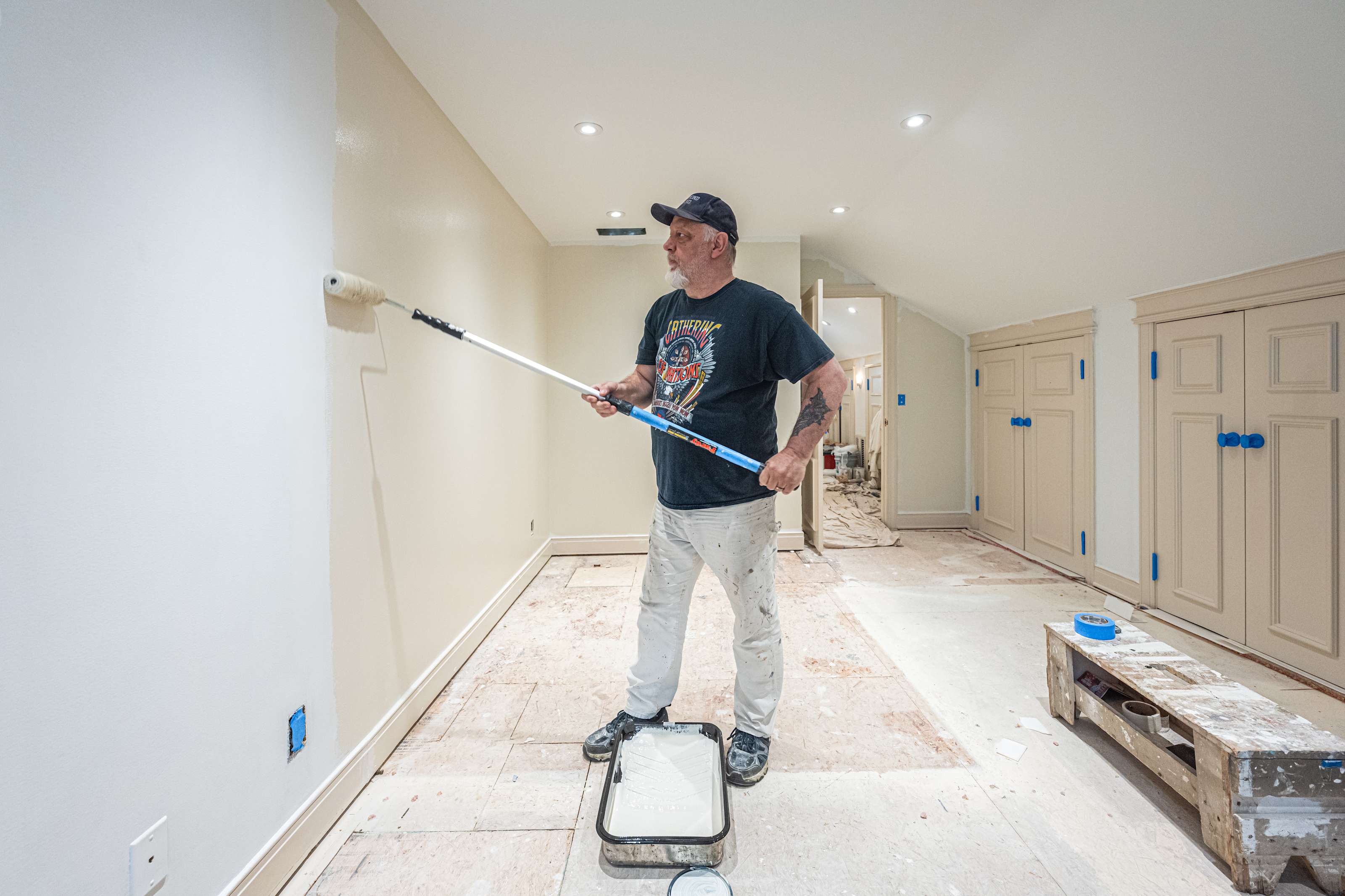man painting wall with white paint