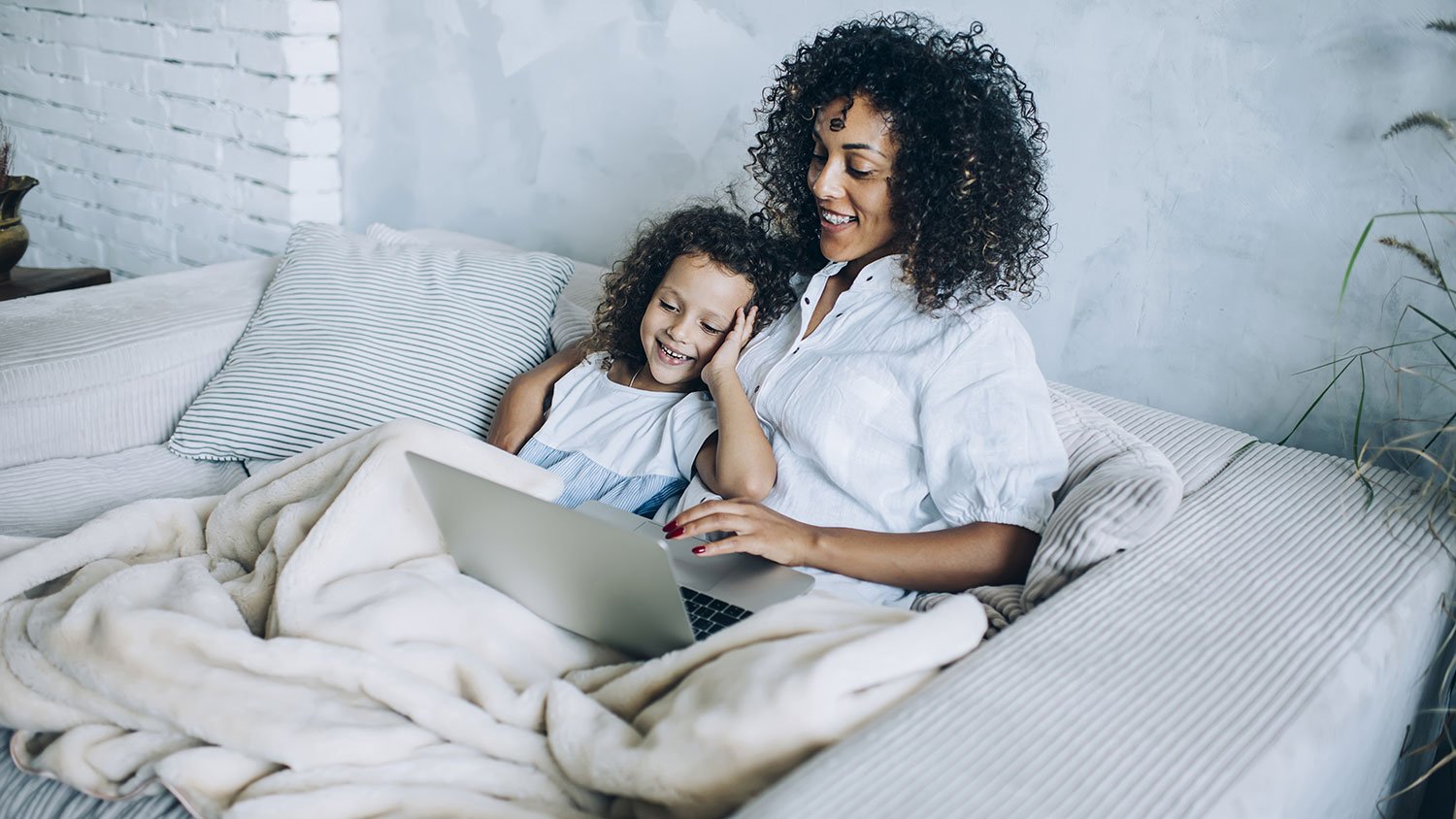 Mother and little daughter snuggling on the couch
