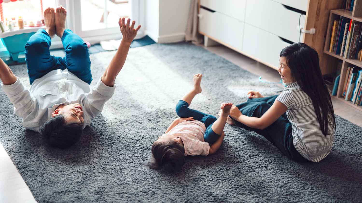 Father and daughters playing on a dark gray carpet
