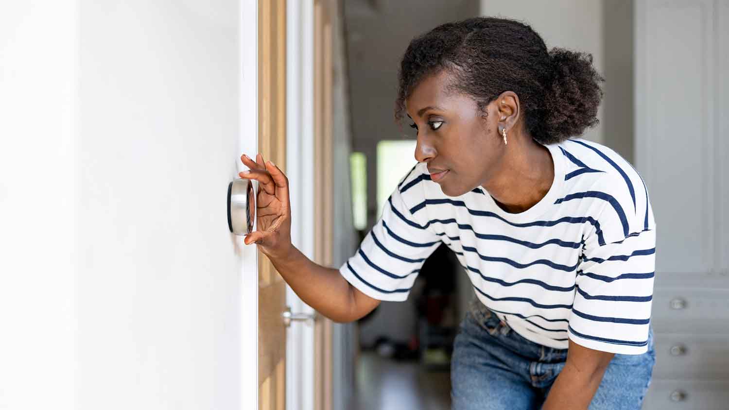 Woman setting up thermostat in the room