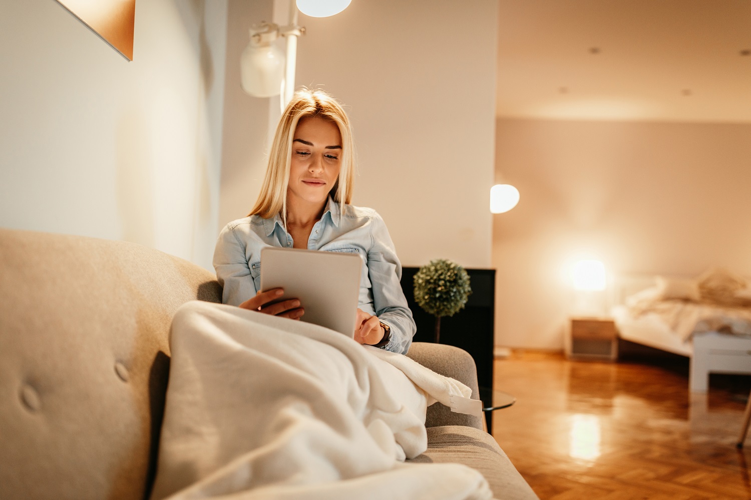 Woman reading comfortably under blanket